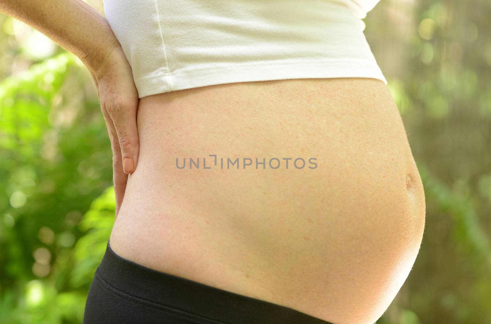 pregnant woman with hands on back who is experiencing back pain