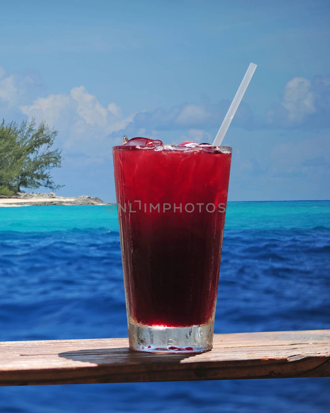 Rum punch or fruity drink in a tropical paradise with a turquoise ocean and clear blue water