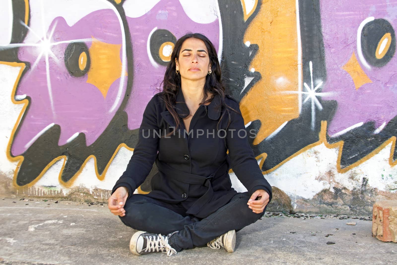 Woman in meditation in front of a graffiti wall