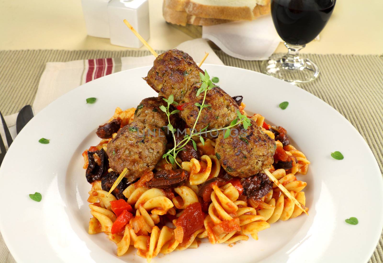 Delicious beef meatballs on tomato and olive pasta with bread and wine.