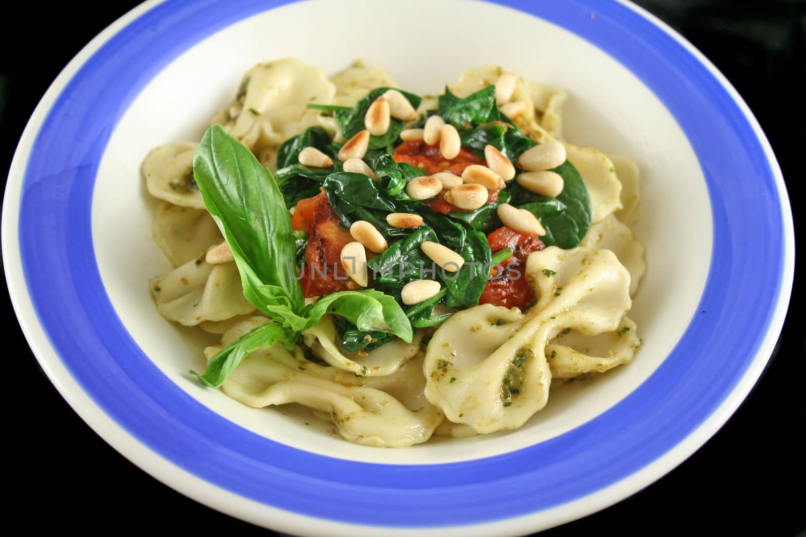 Pasta with pesto and spinach, cherry tomatoes and pine nuts.