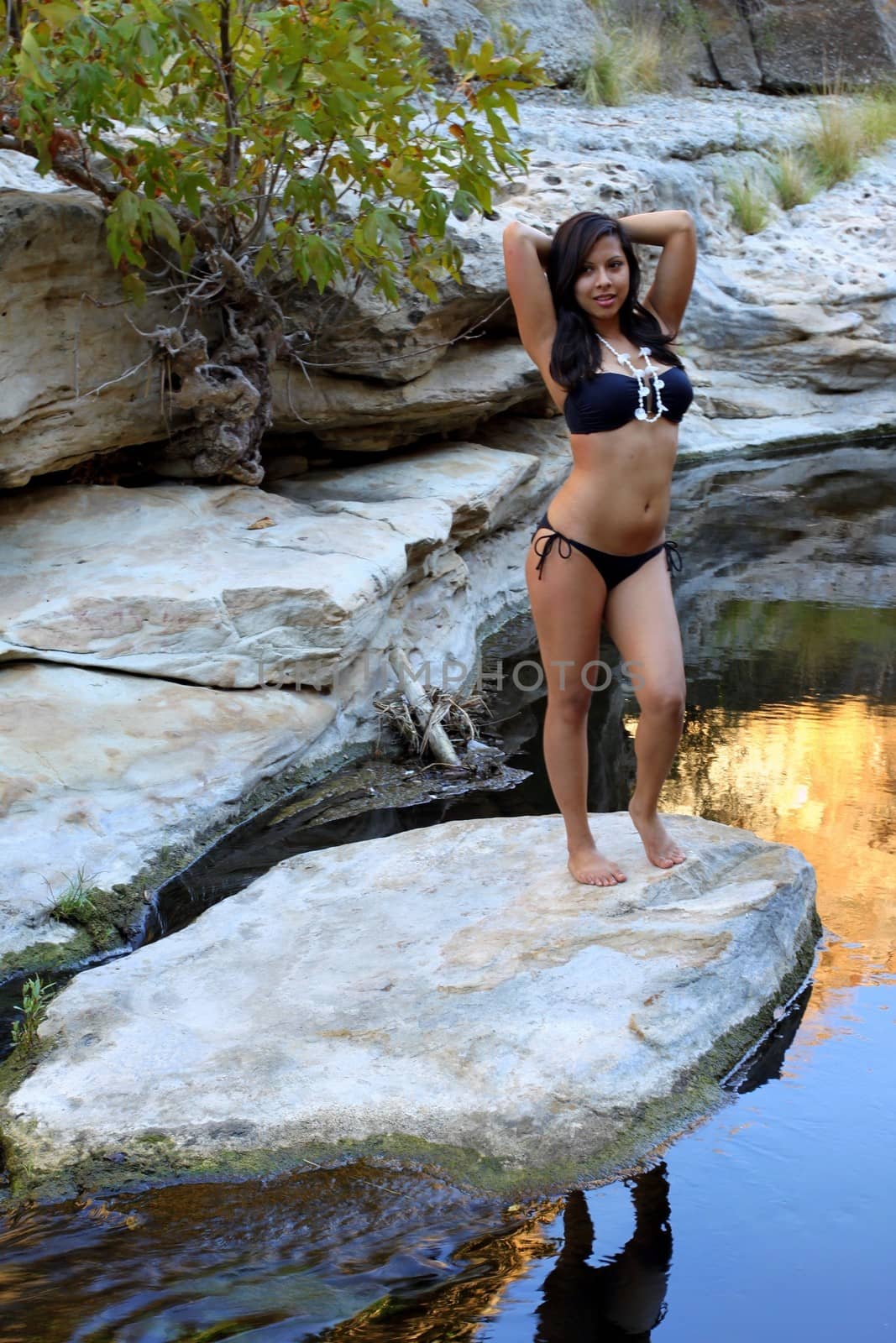 Young Hispanic woman with bikini near a creek.