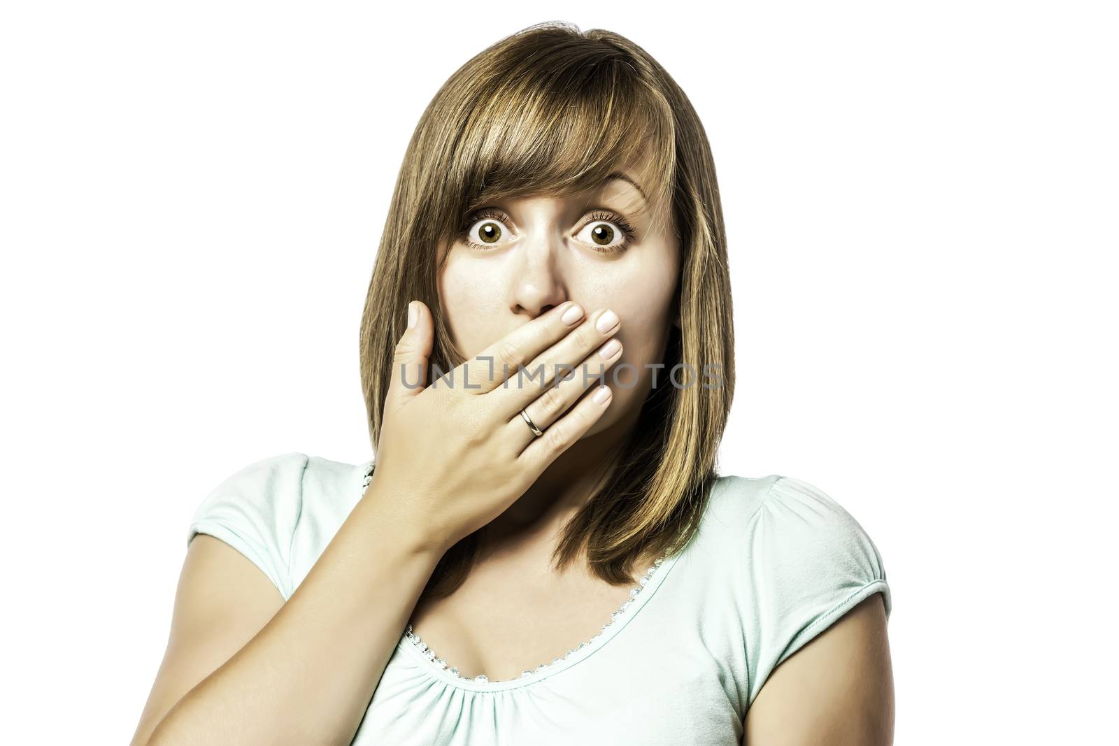 Shocked young girl who is afraid and keeps up with eyes wide open hand over her mouth, isolated on white background