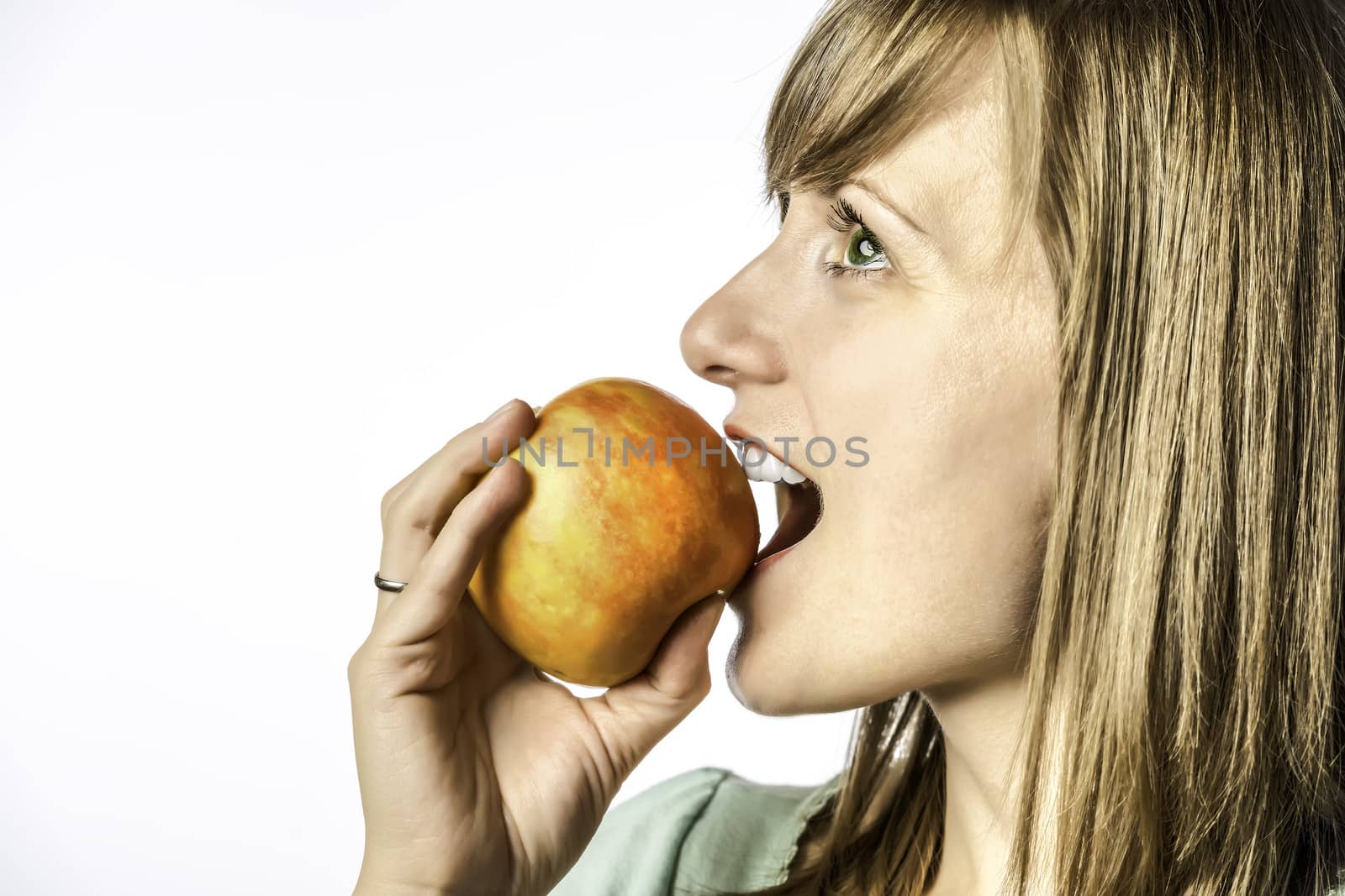 Portrait of a young girl biting into a red yellow apple, isolated on white background