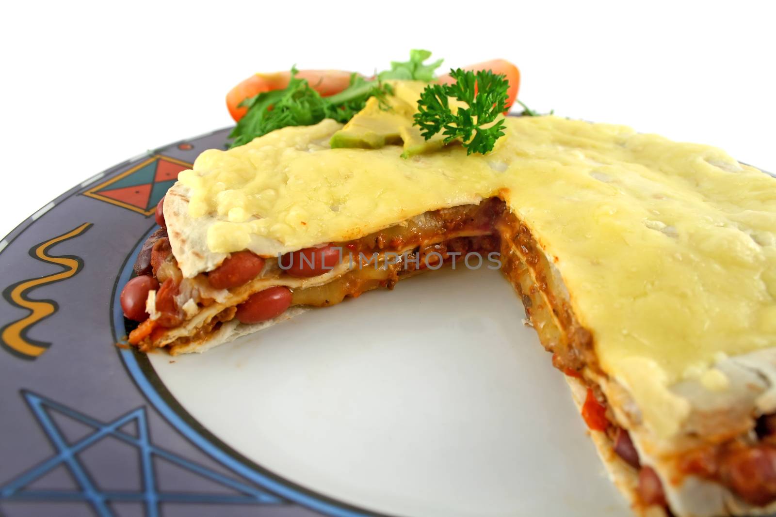 A beef and bean Mexican tortilla stack with cheese and salad with a slice cut.