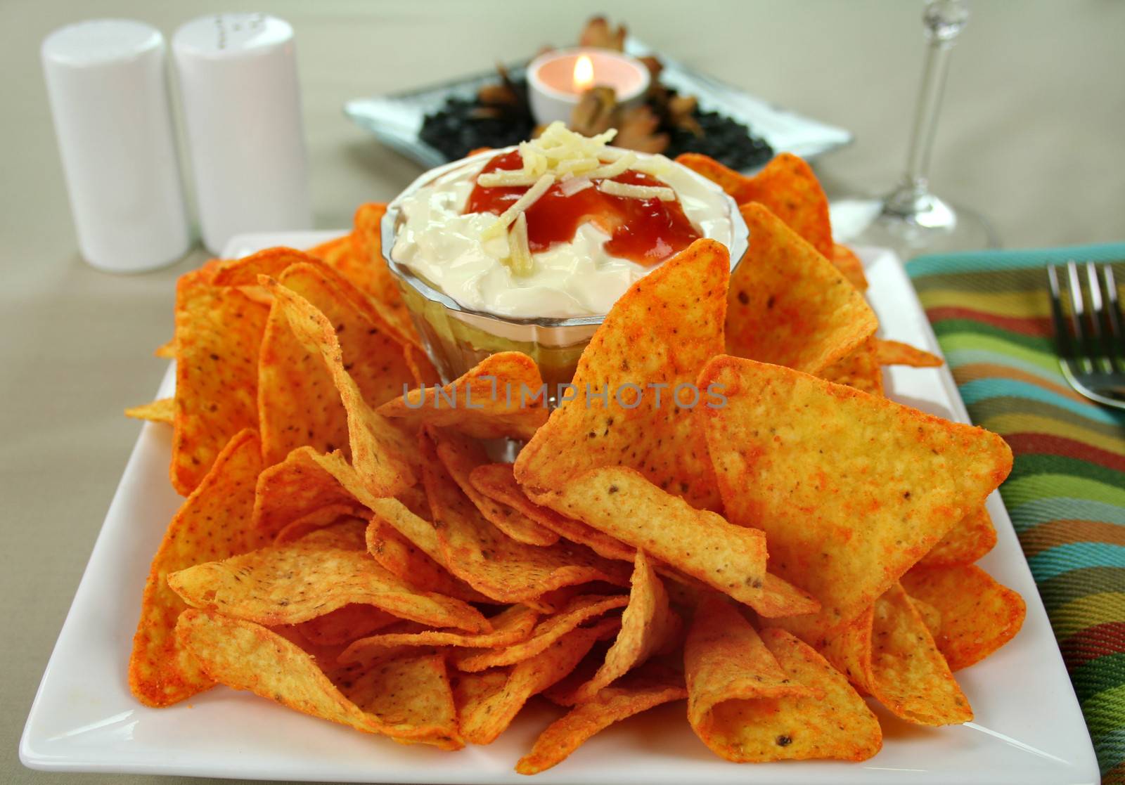 Nachos and Mexican dip topped with sour cream, salsa and grated cheese.