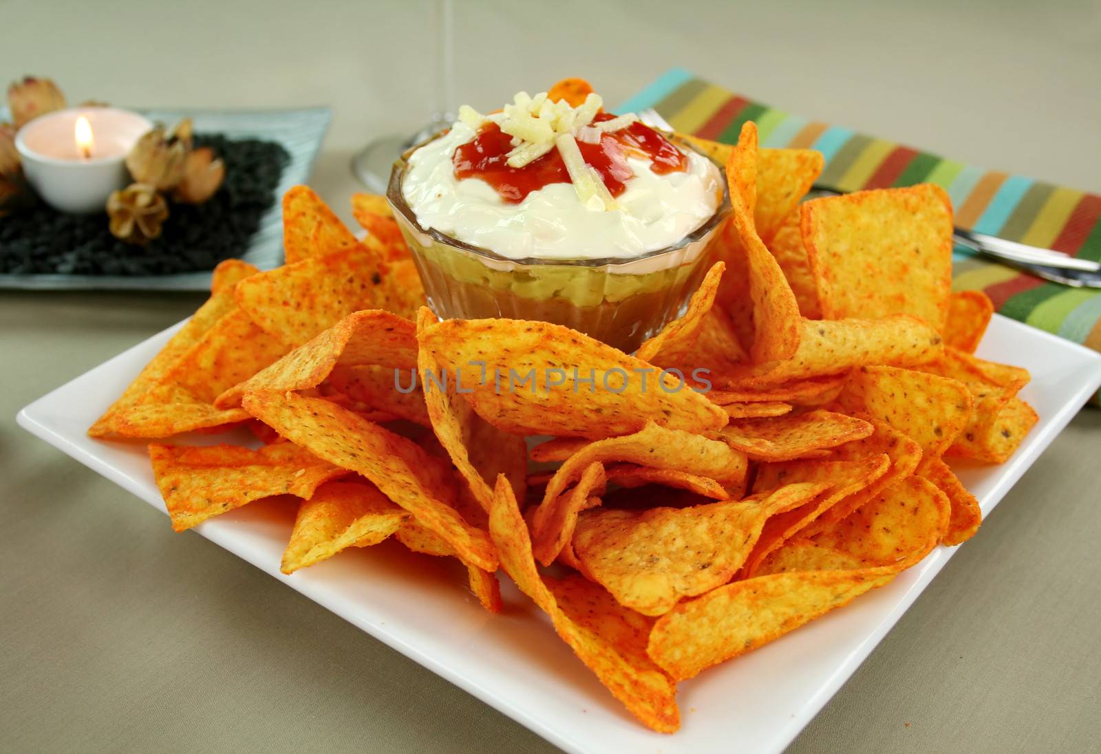 Nachos and Mexican dip topped with sour cream, salsa and grated cheese.