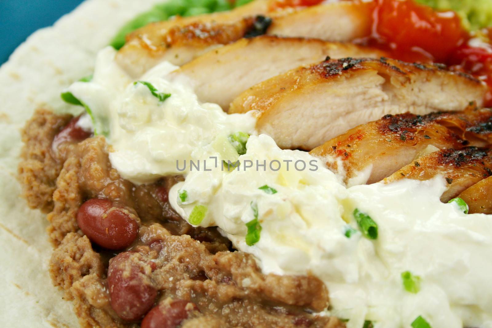 Open chicken tortilla with refried beans and sour cream with chives.