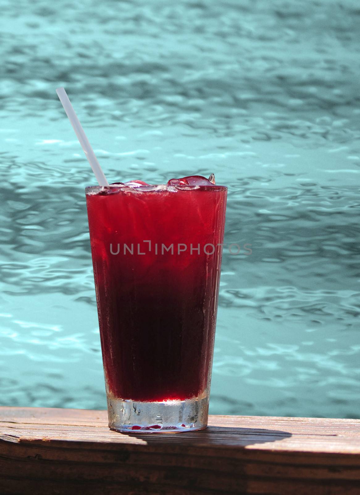 Red tropical drink by pool on warm summer day or on vacation