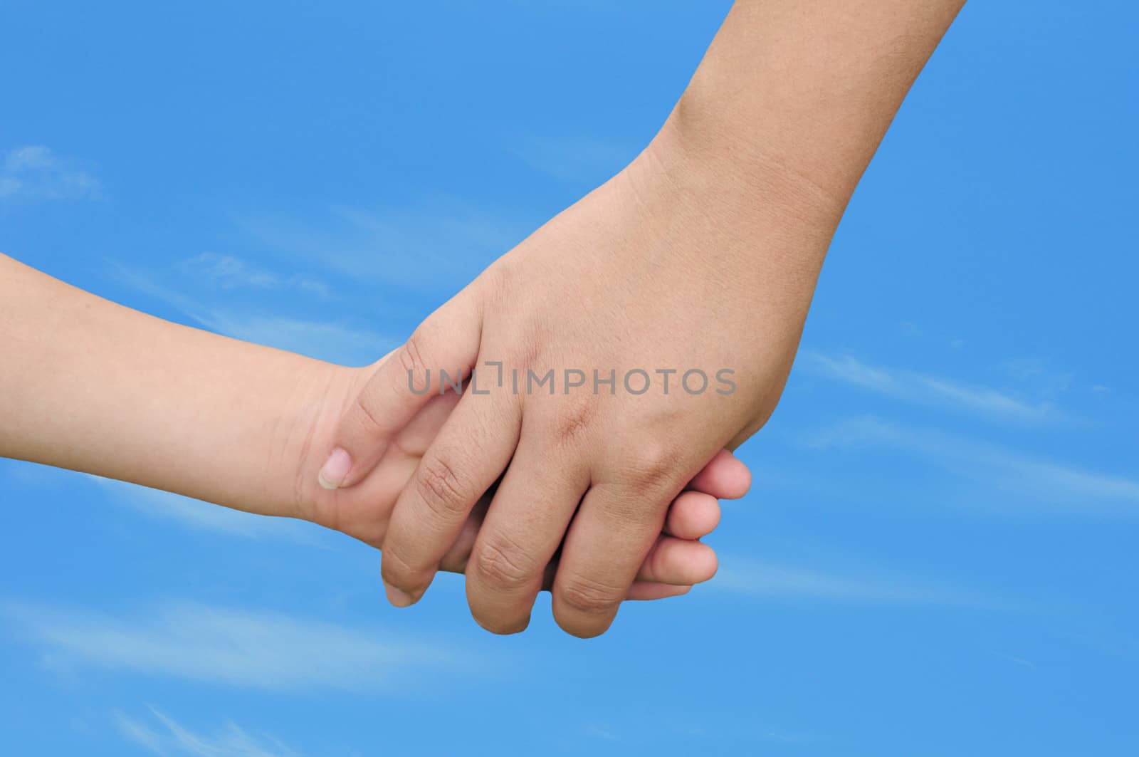 motherhood concept with a woman holding a child's hand outdoors on a warm day