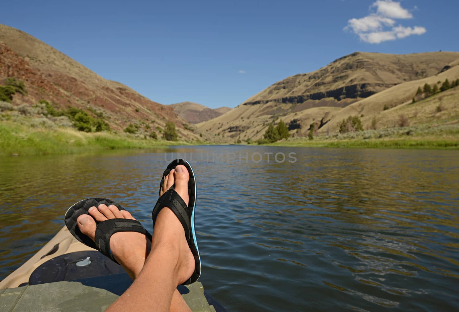feet up while relaxing during leisure time on a river with mountains 