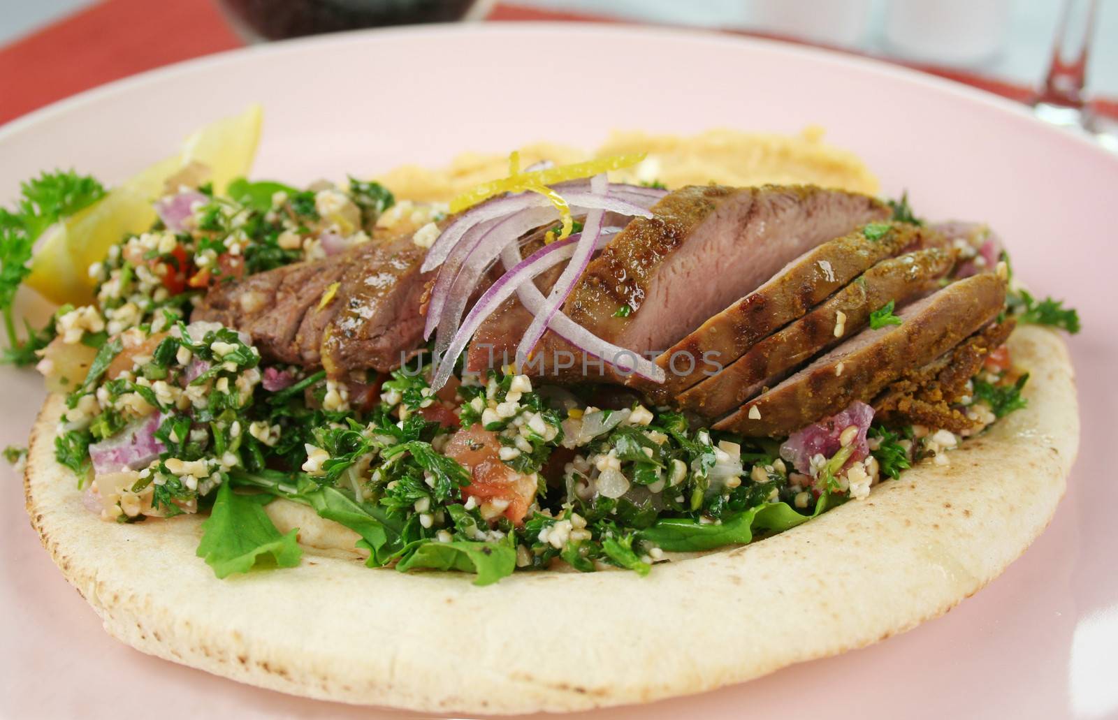 Middle Eastern lamb fillet on pita bread with hommus and tabouleh and lemon parsley.