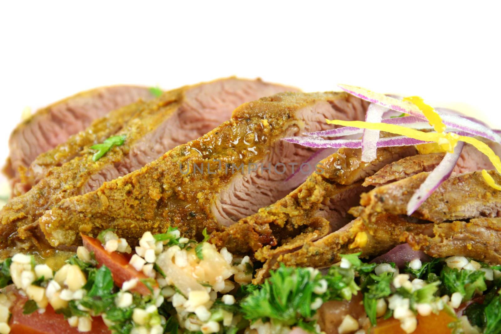 Sliced Middle Eastern lamb fillet with hommus and tabouleh.