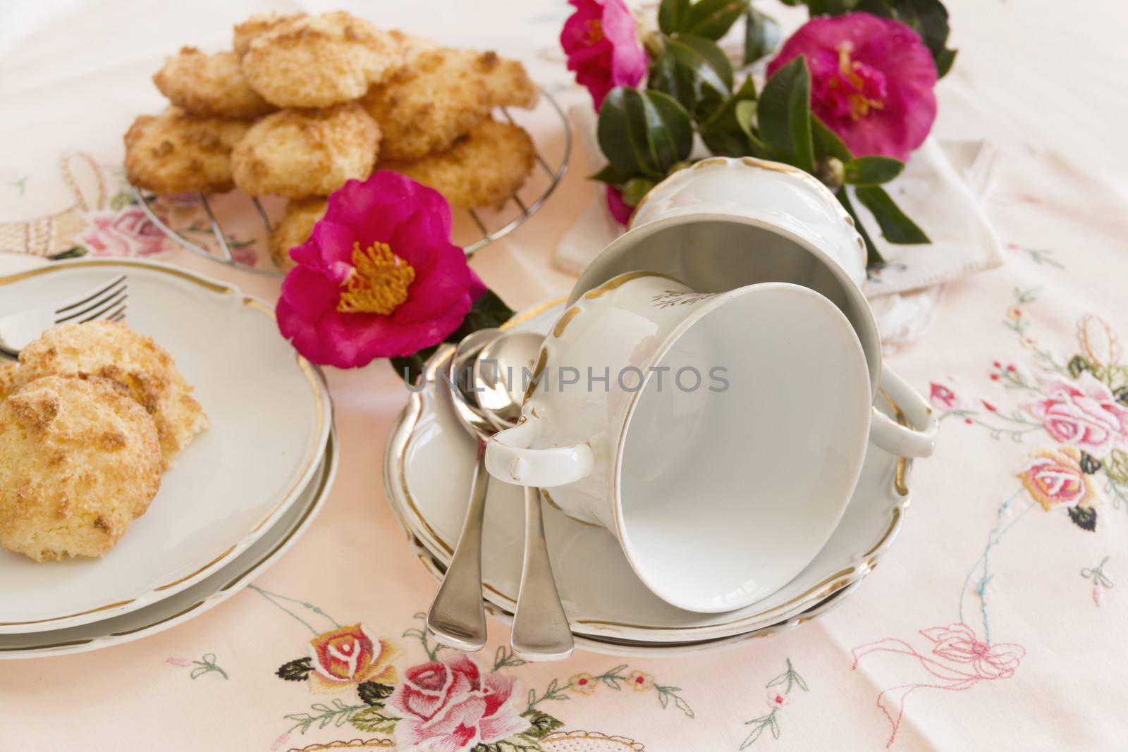 Beautiful camellias with two vintage teacups laying on saucers with coconut macaroons.