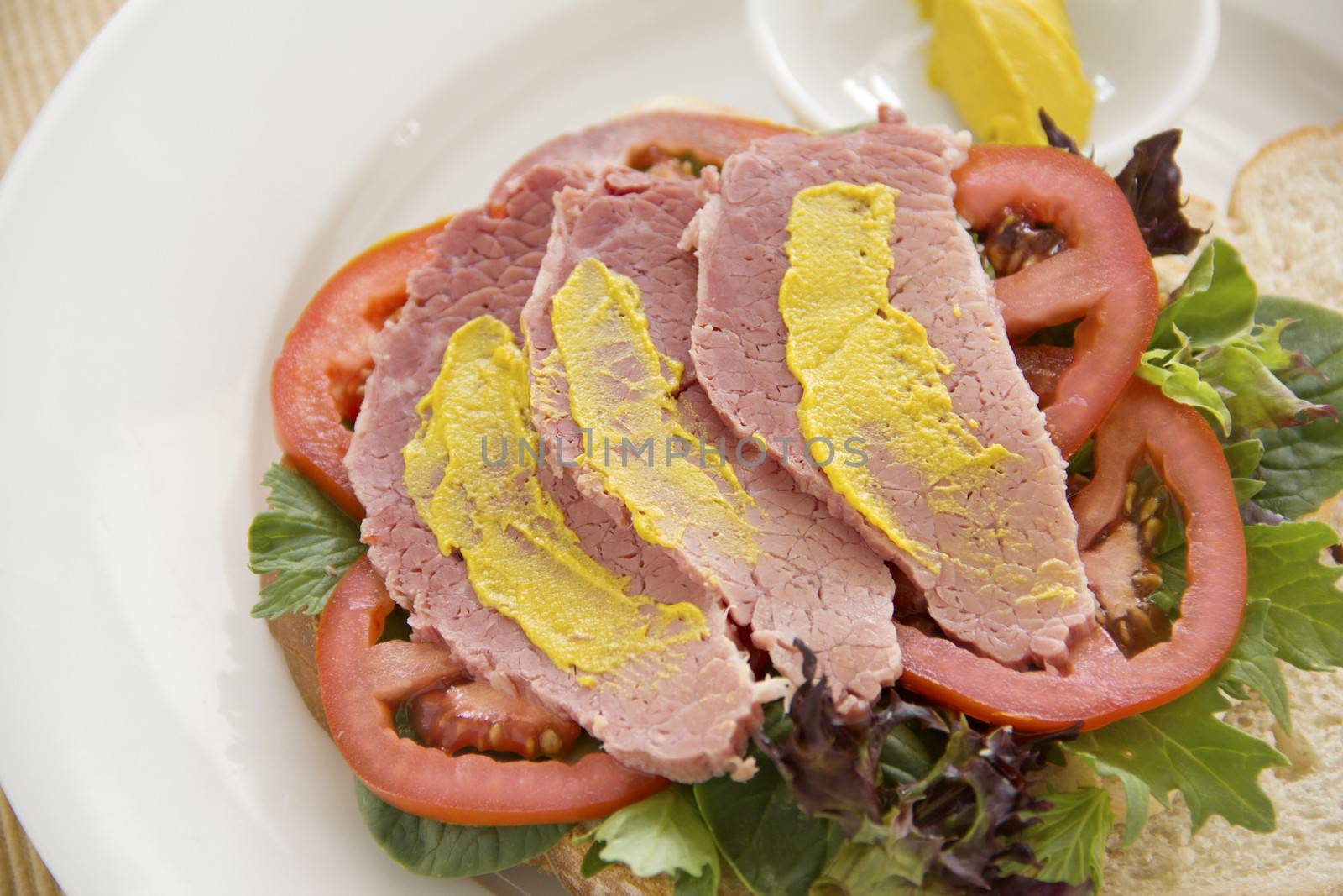 Delicious open corn beef open sandwich with mustard and fresh garden salad.