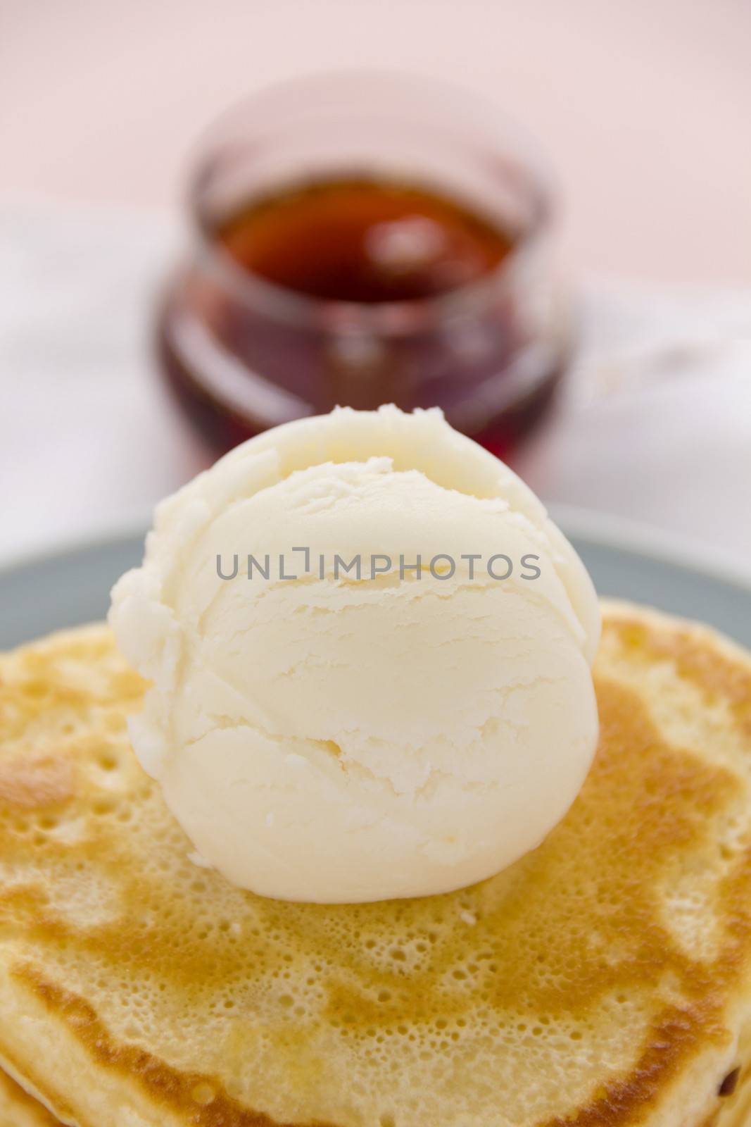 Scoop of vanilla ice cream on a pancake with maple syrup.