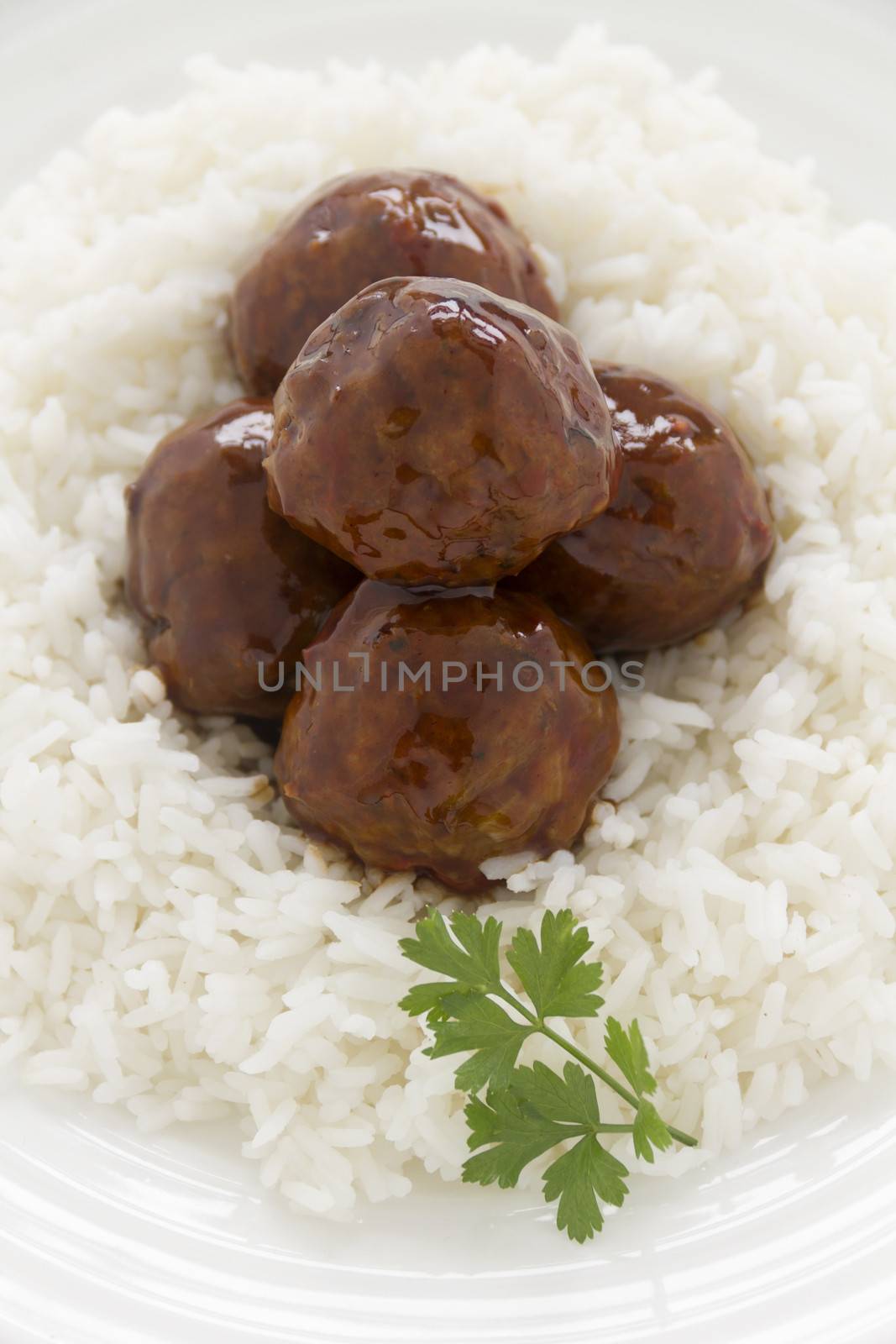 Chinese meat balls in hoisin sauce on a bed of white rice with parsley.