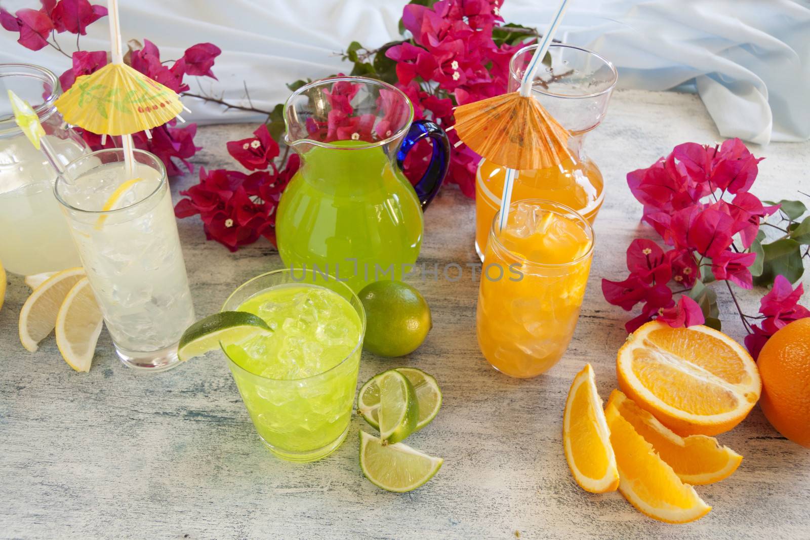 A selection of summer drinks with ice including lime, orange and lemon.