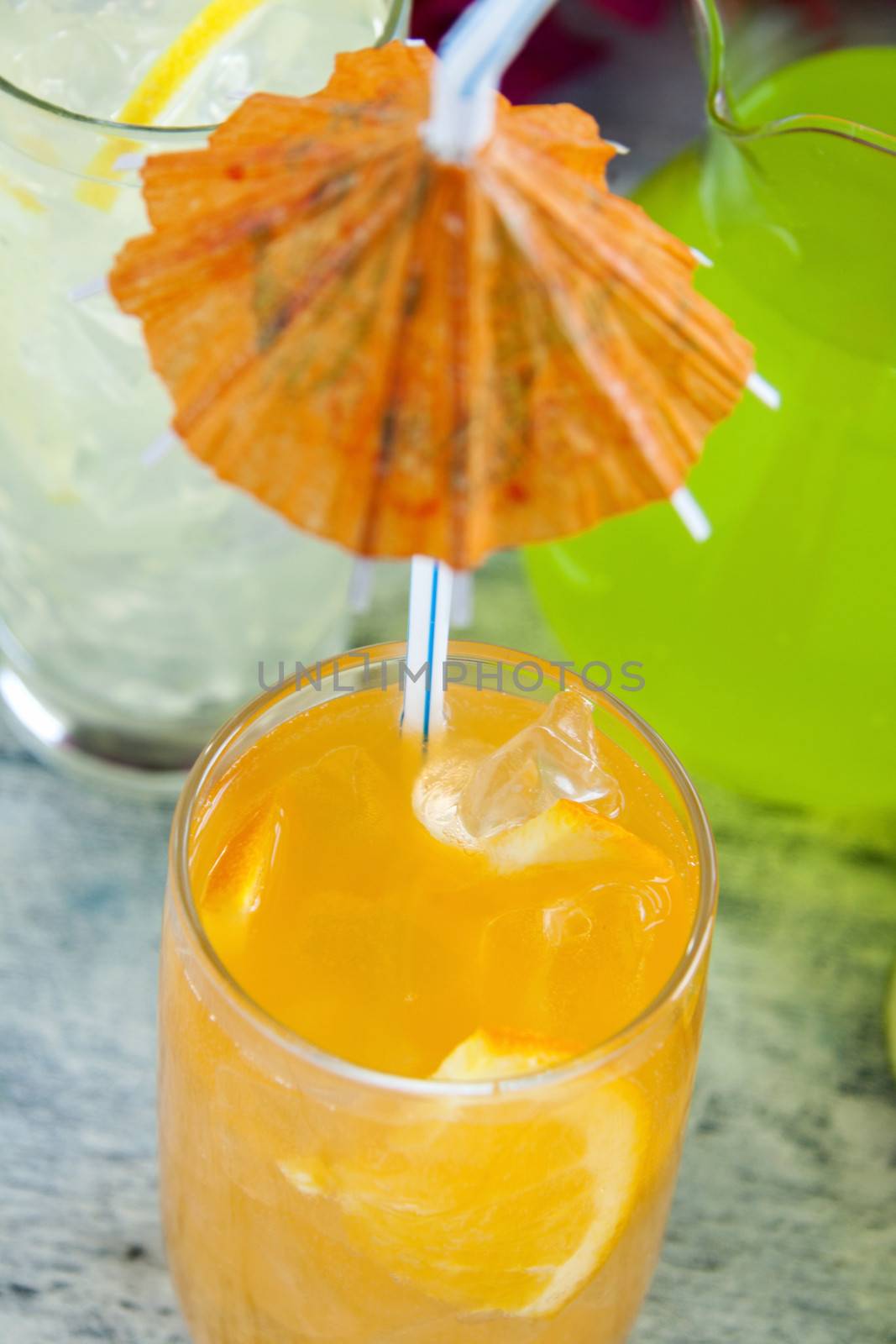 Delicious quenching orange drink with ice and a cocktail umbrella.