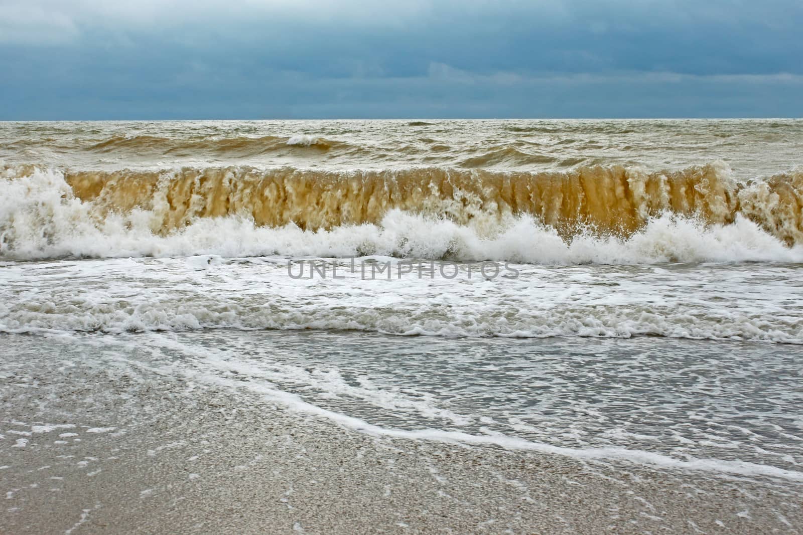 Big stormy wave with sand contaminated water directed ashore