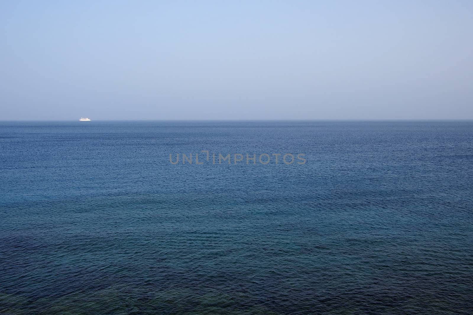 Ocean landscape under blue sky with sailboat