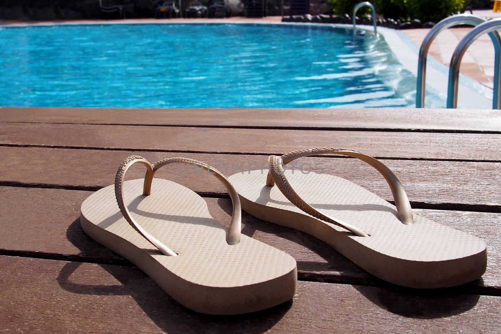Pair of slippers by a swimming pool by stockyimages