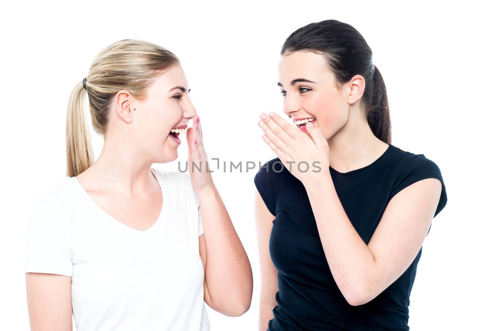 Two pretty young girls laughing loud while gossiping