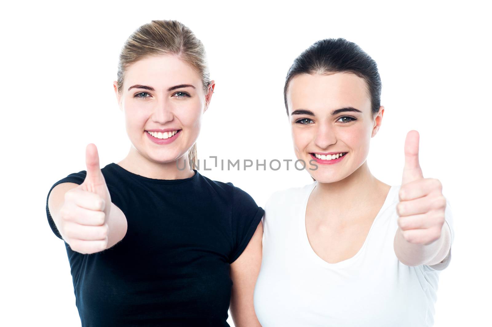 Two girls cheering via with thumbs up gesture by stockyimages
