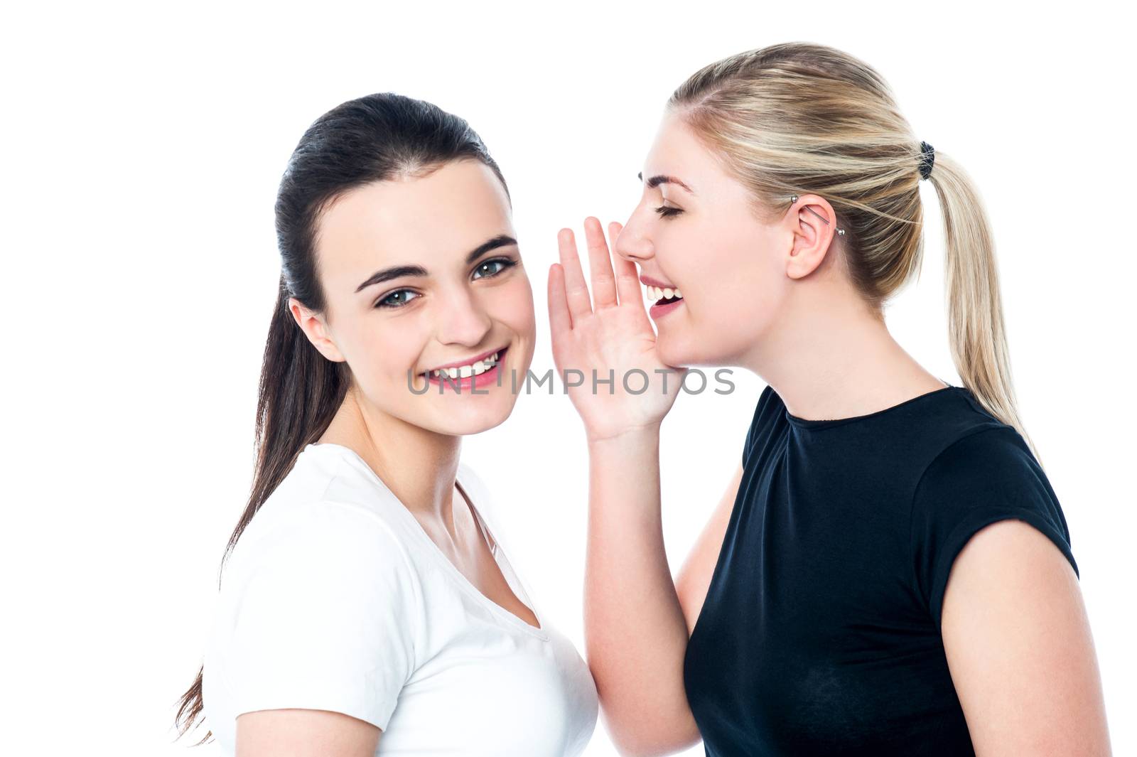 Two beautiful smiling girls sharing a secret