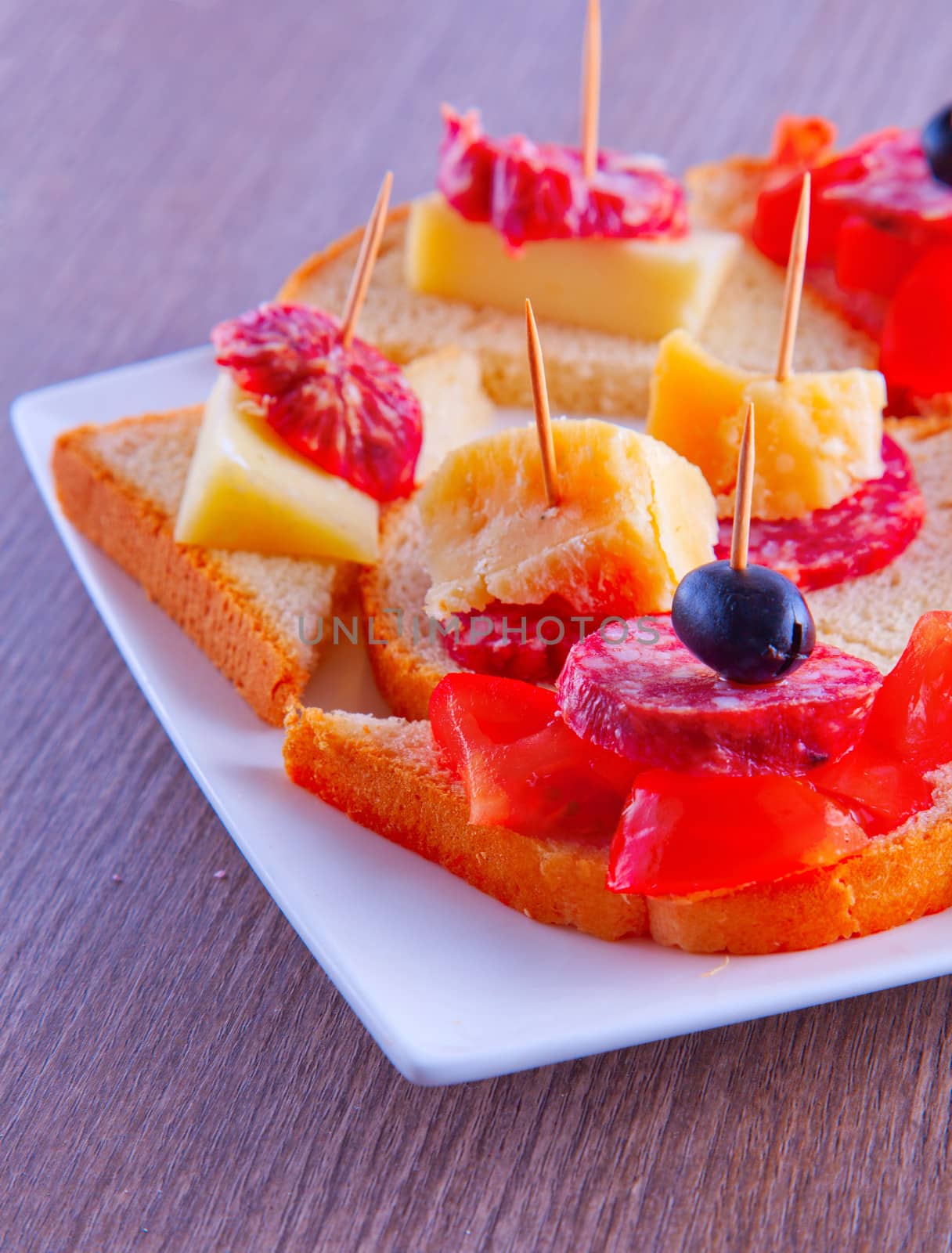 A sausage and tomato appetizers over a white plate