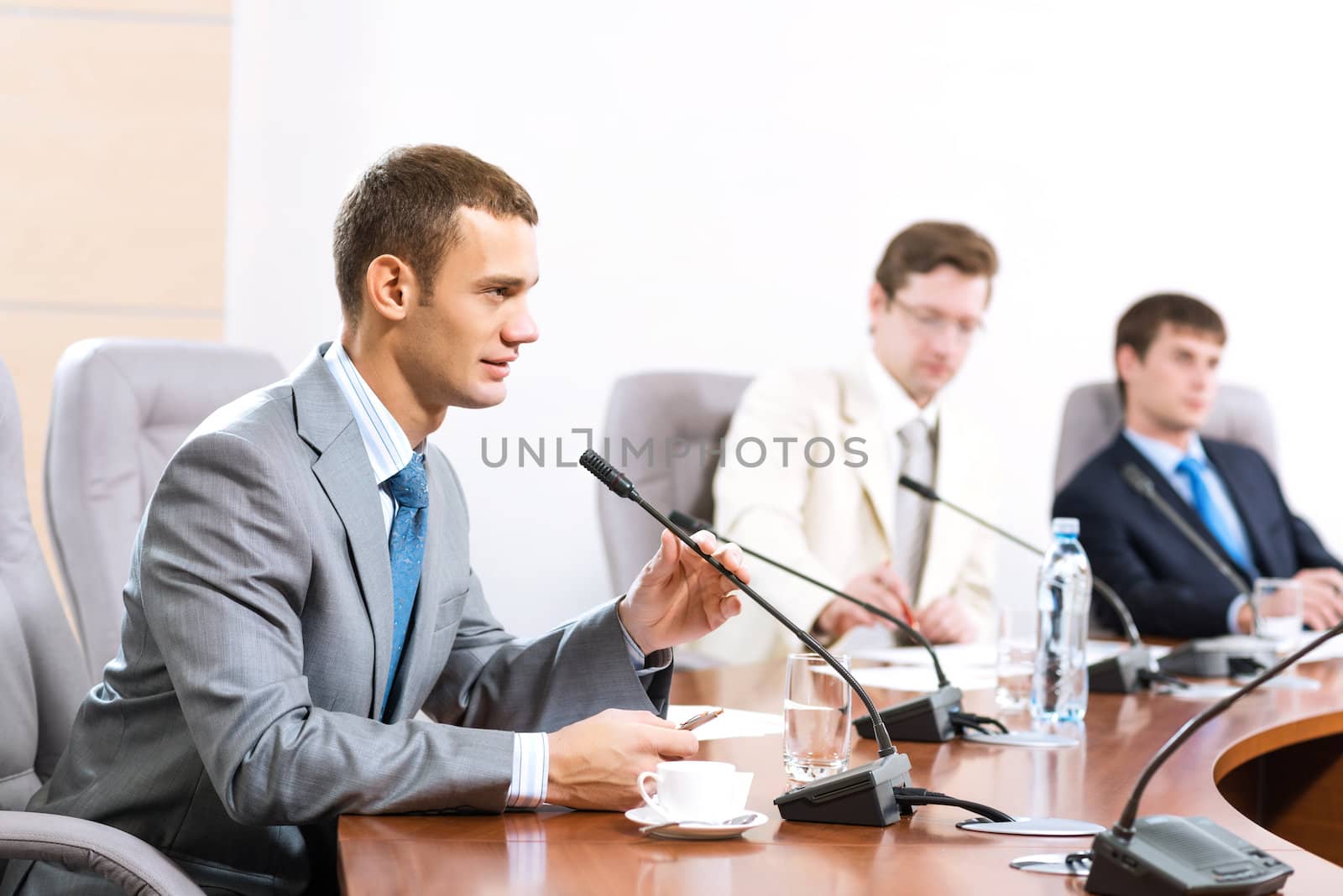 Portrait of a businessman, said into the microphone, in the background colleagues communicate with each other