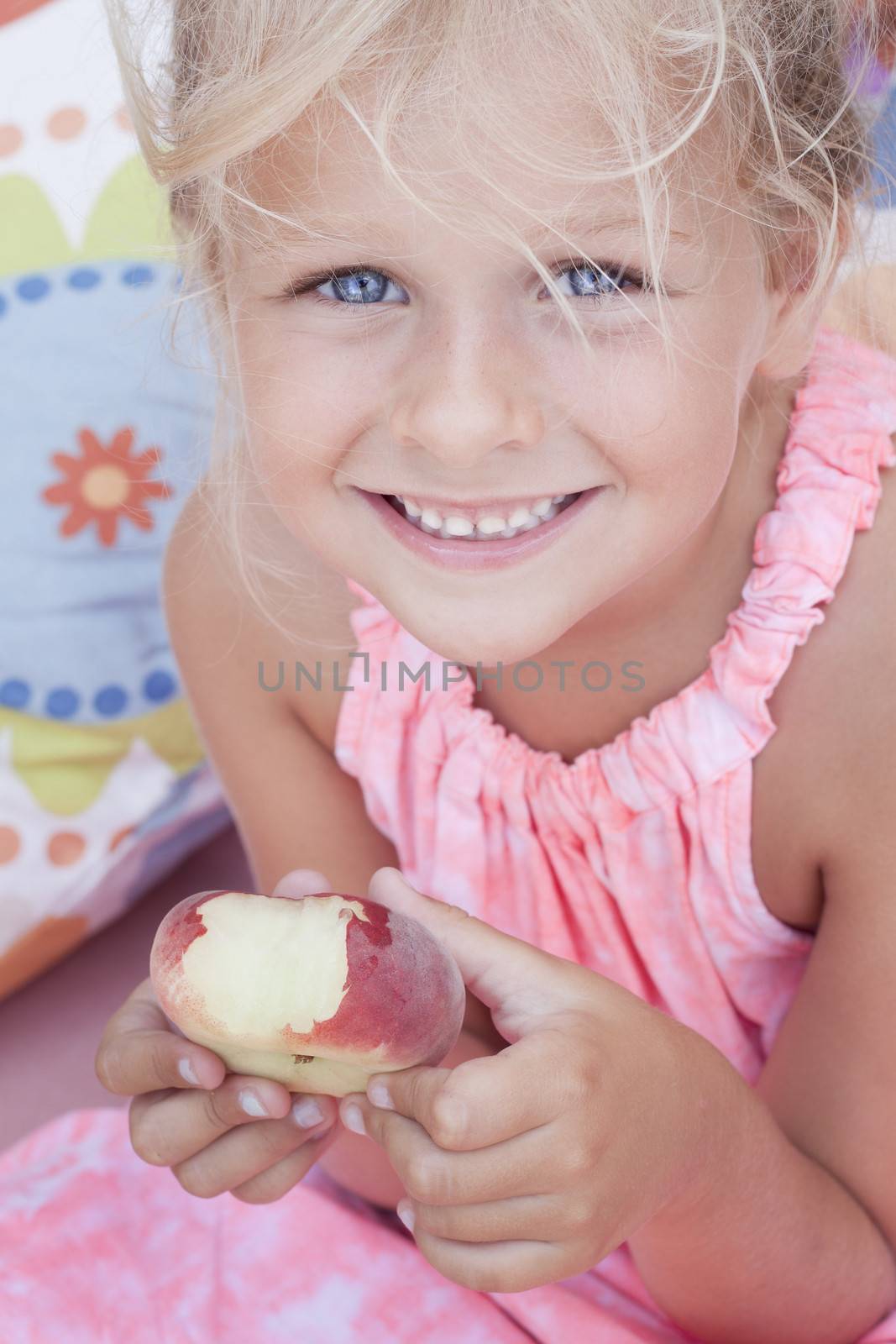 A girl holding a bitten flat peach, so called peento