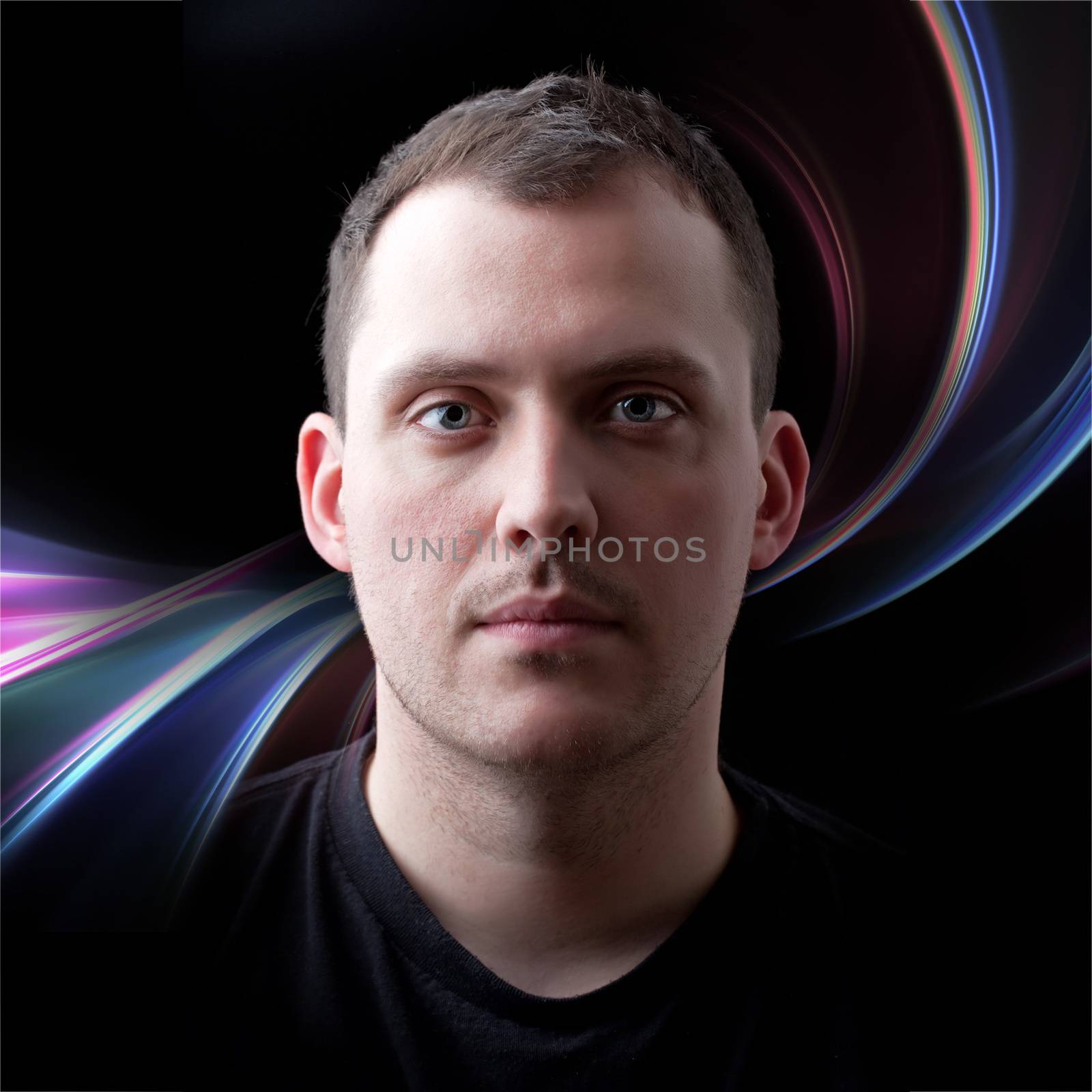 Low key portrait of a serious man in his late twenties with colorful abstract backdrop.  Shallow depth of field.