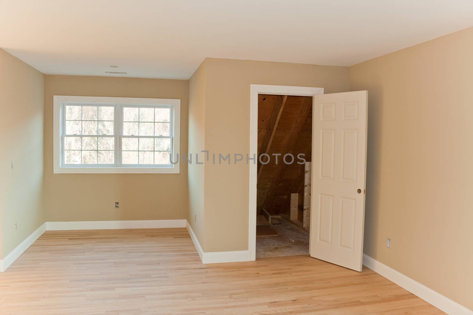 New home construction interior room with unfinished wood floors and twin closets.  The electrical and hvac connections also are partially unfinished.