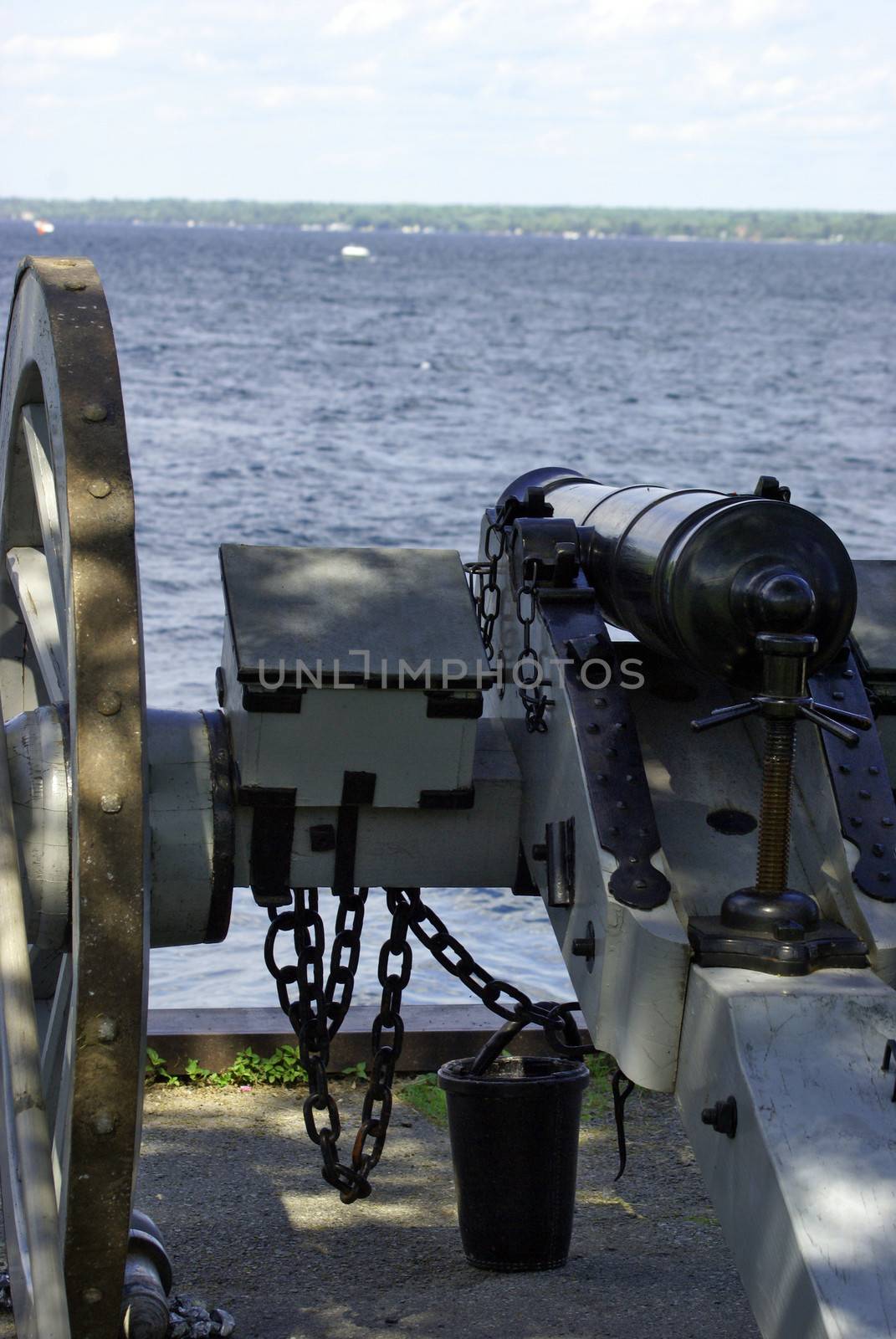 An antique canon on the shore aiming out to the water.