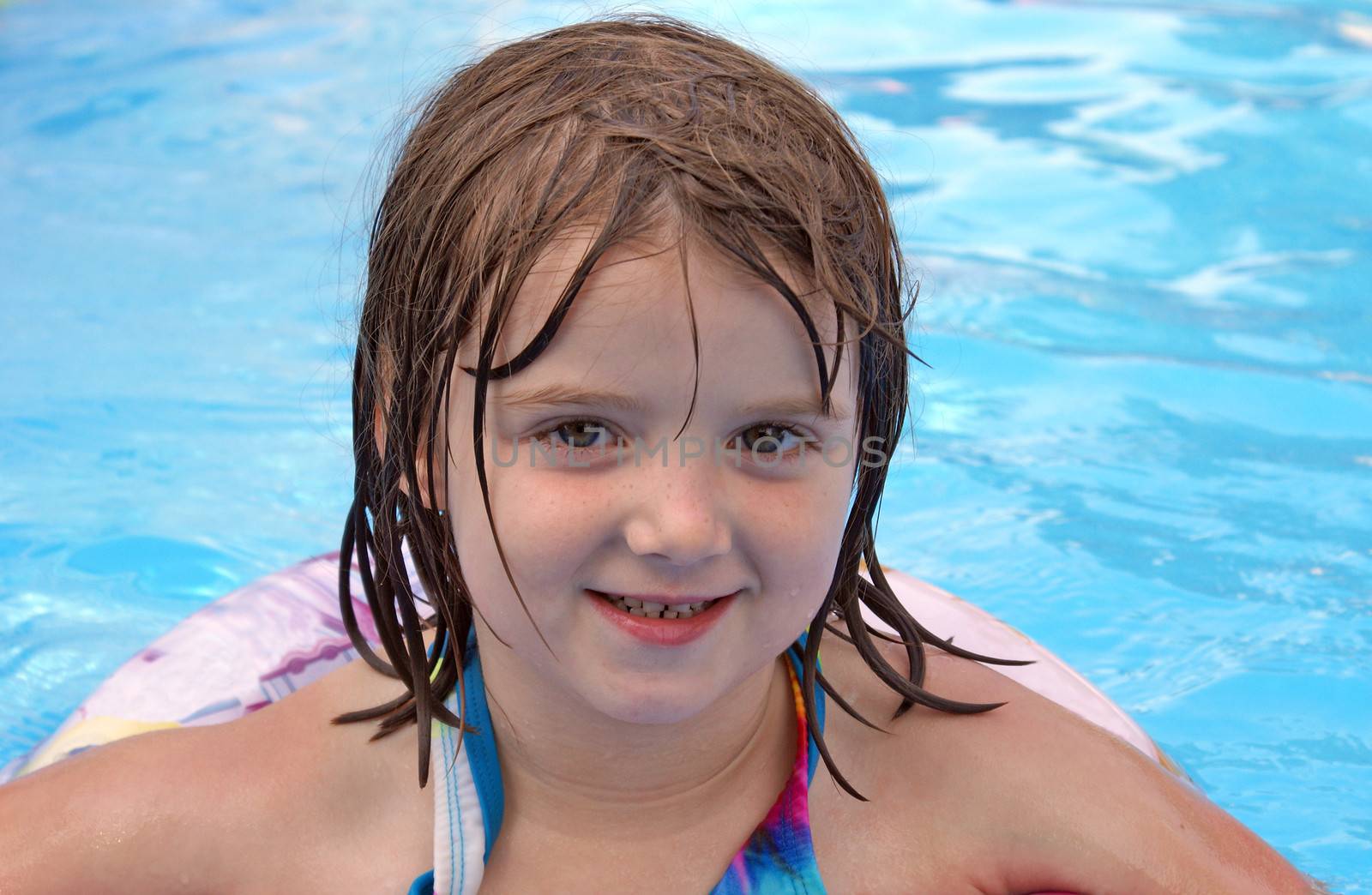 An adorable five year old girl enjoys some recreational time in the pool.