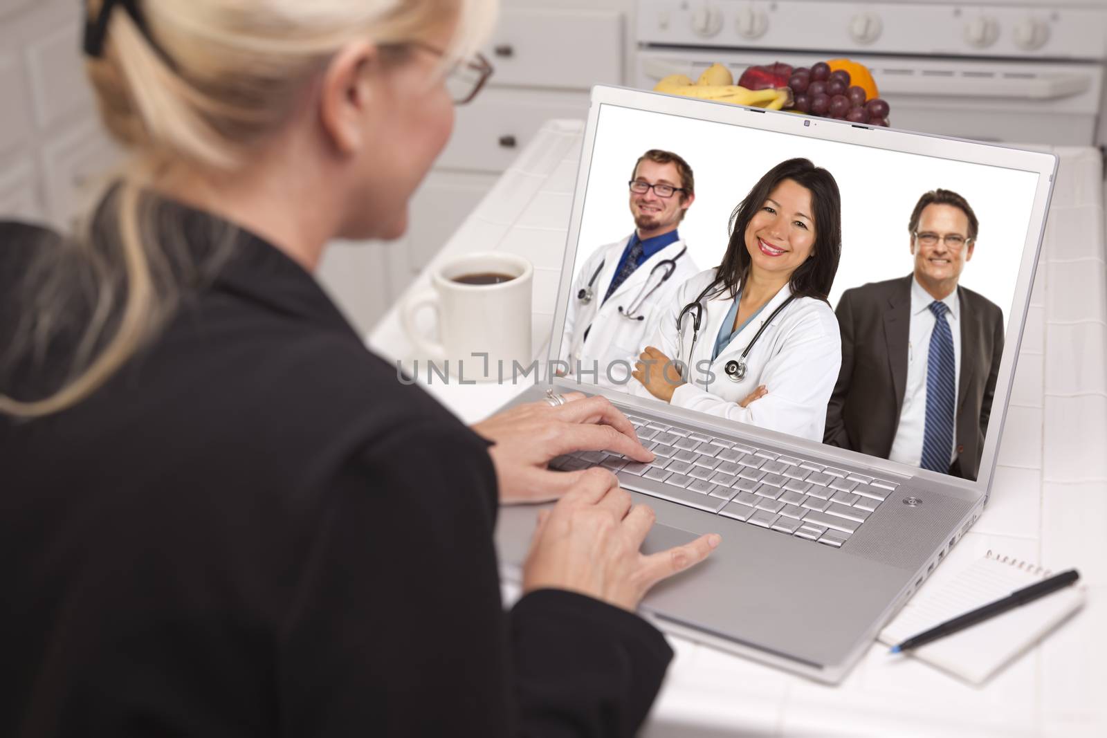 Woman In Kitchen Using Laptop, Online with Nurses or Doctors by Feverpitched