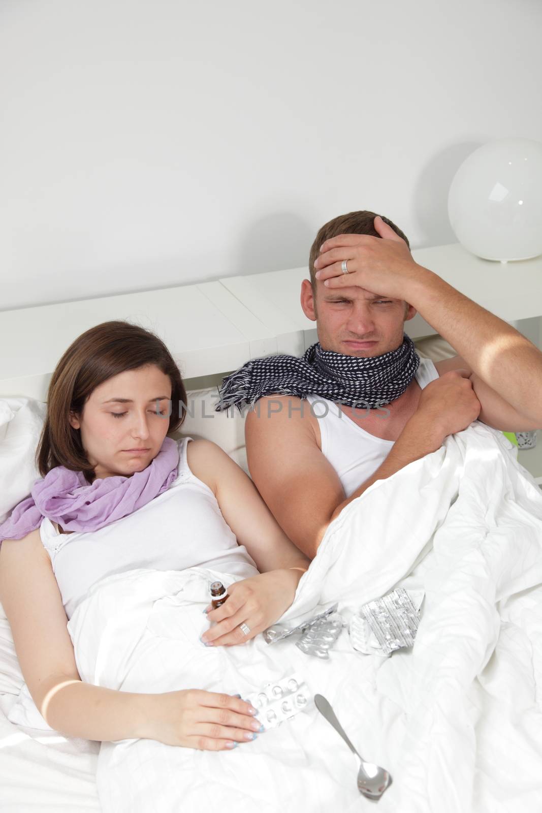 Portrait of a young couple in bed together as they both sick