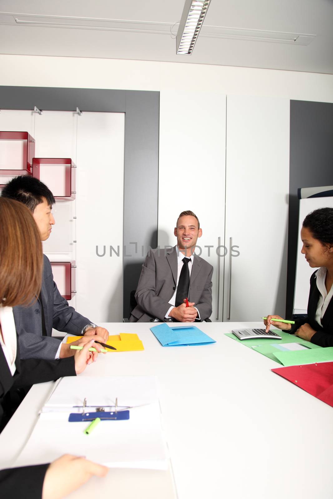 Group of business people listening to colleague addressing office meeting smiling