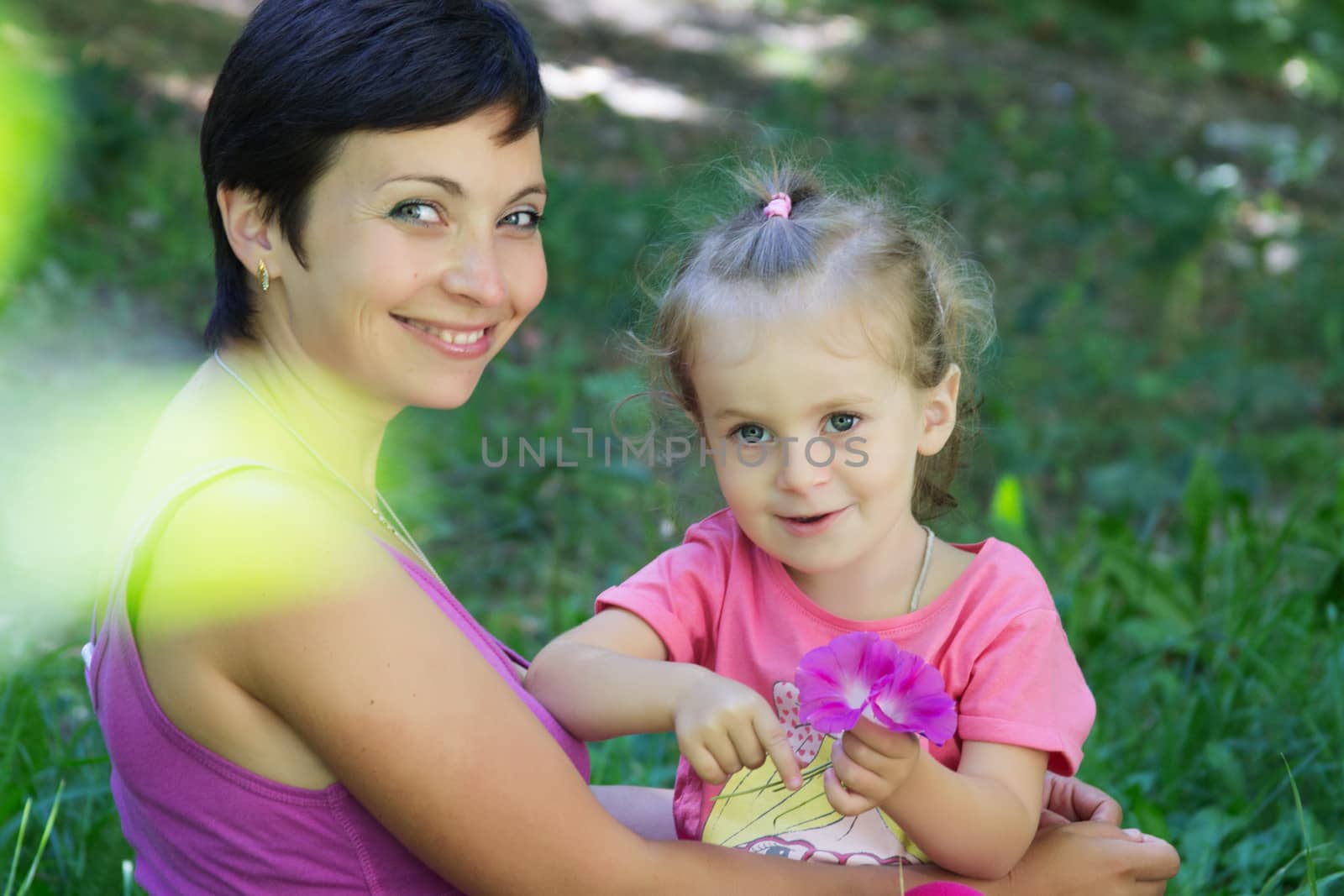 Happy mother and little daughter playing in meadow