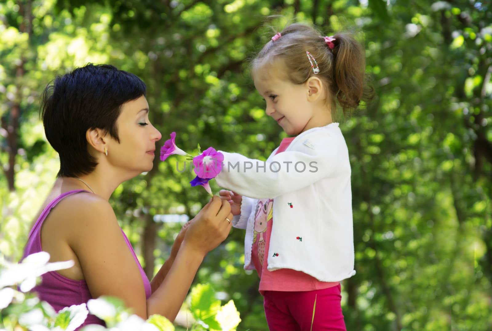 Mother and daughter playing among grass with flowers