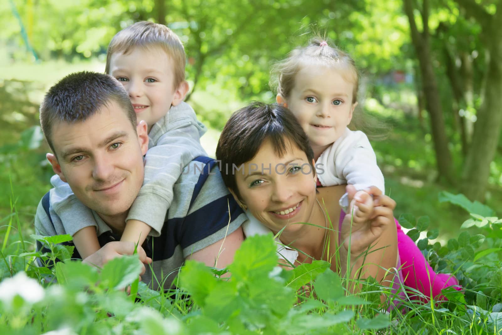 Happy family with two children lying down in the park