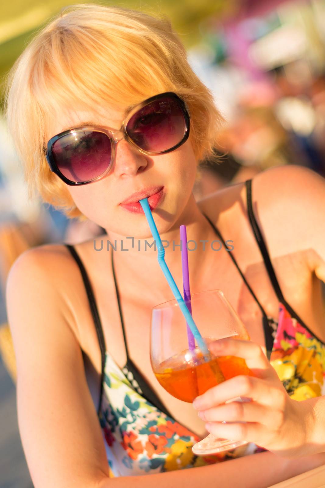 Cute young lady  drinking cocktail on the outdoor terrace on a lovely sunny  day.