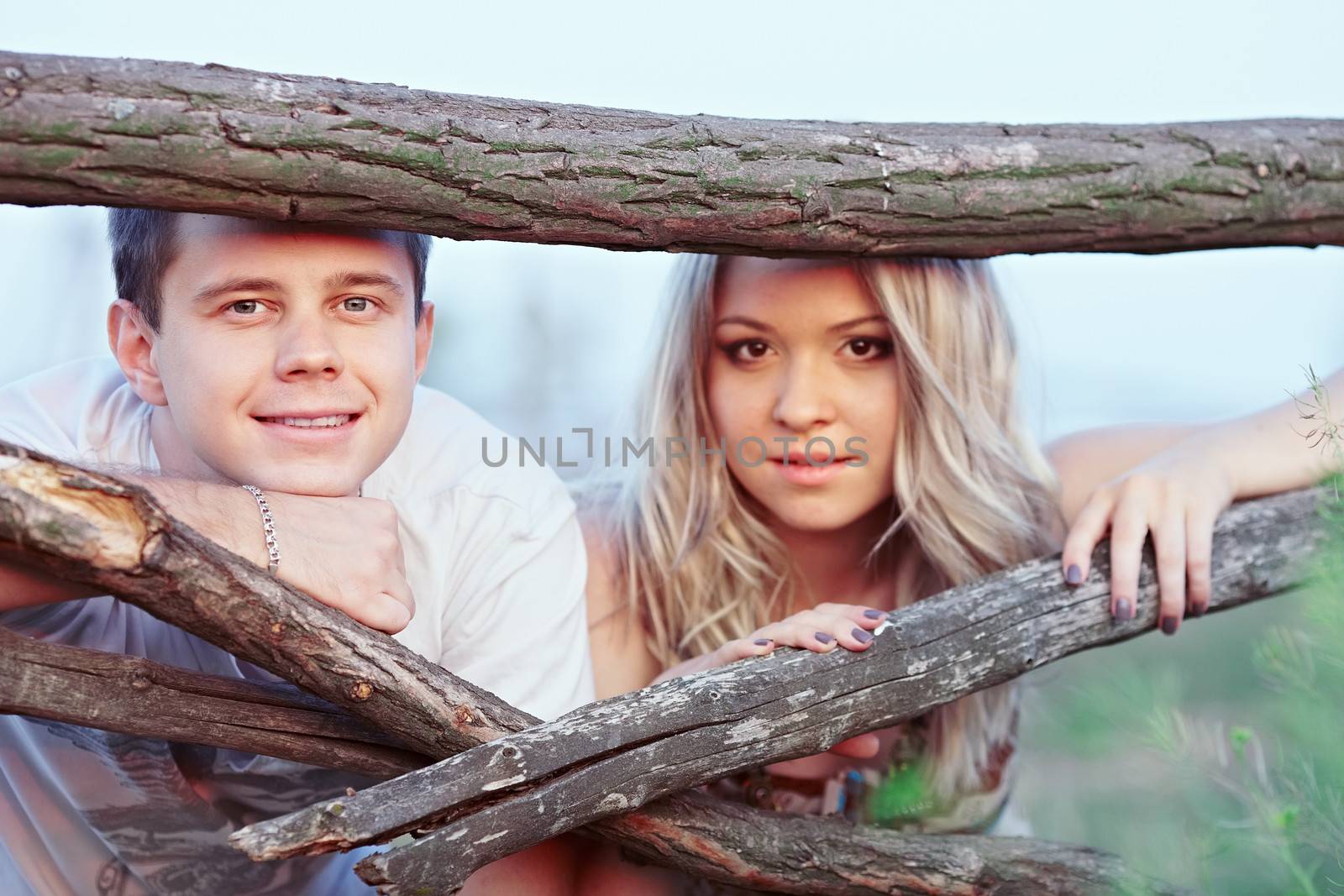 Young couple at sunset near a wooden fence