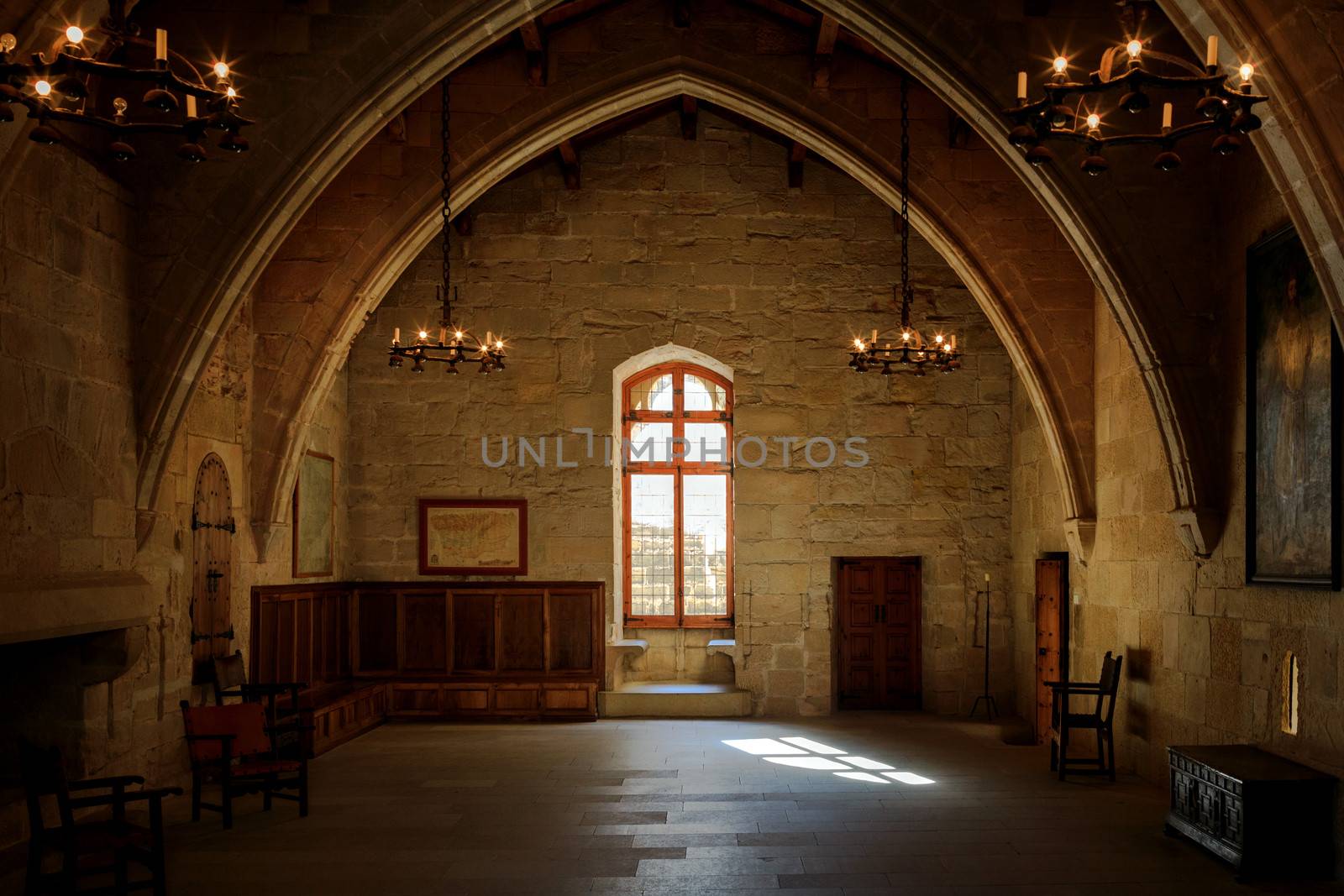Dark old room in Poblet cloister with stained glass window and candelabra, Spain