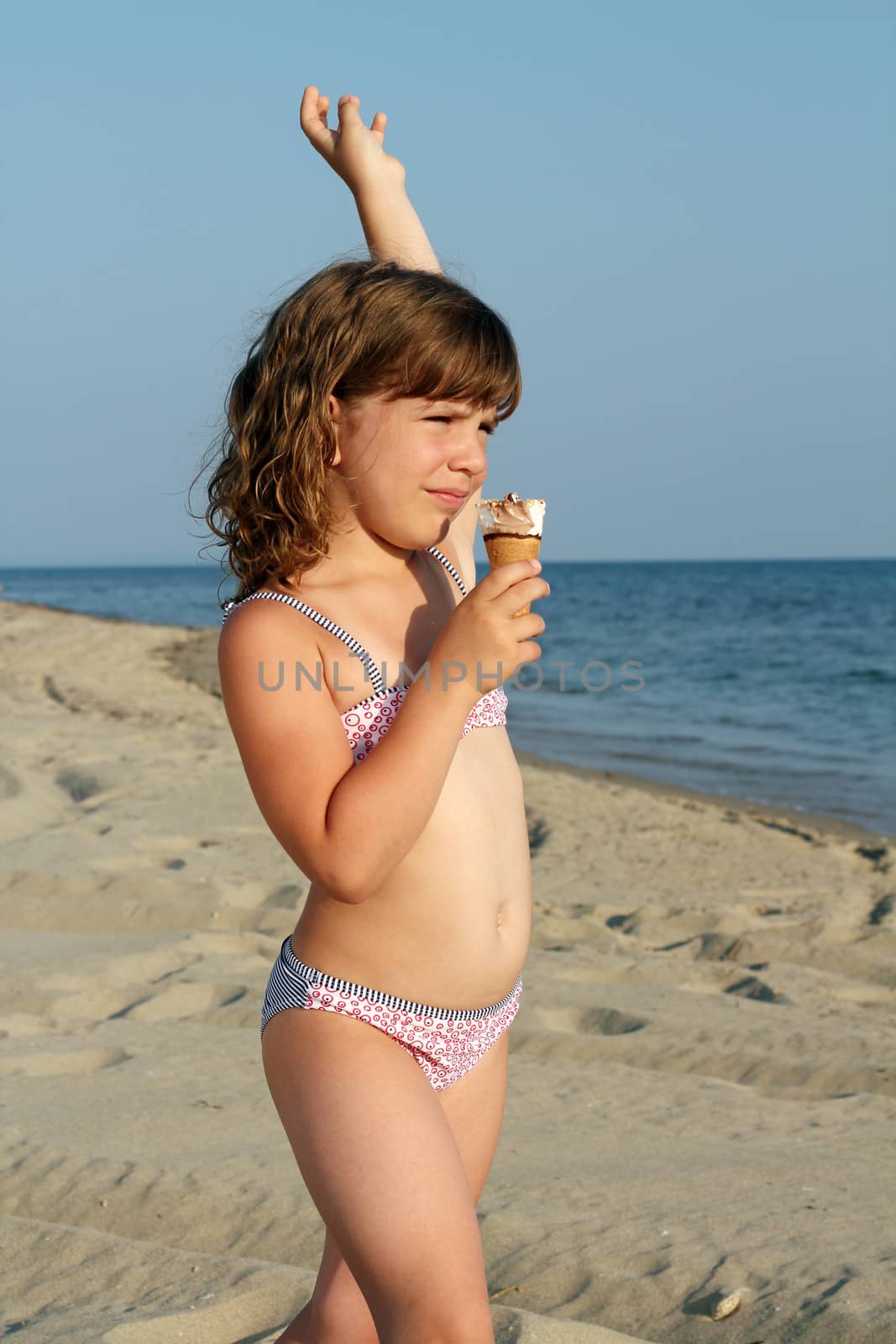 child eat ice cream on beach by goce