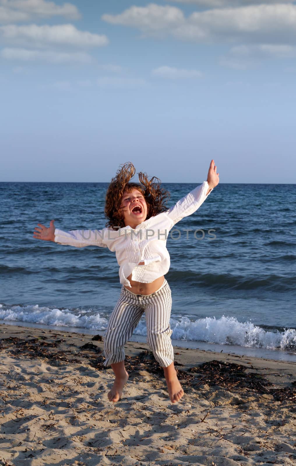 happy child jumping on beach by goce