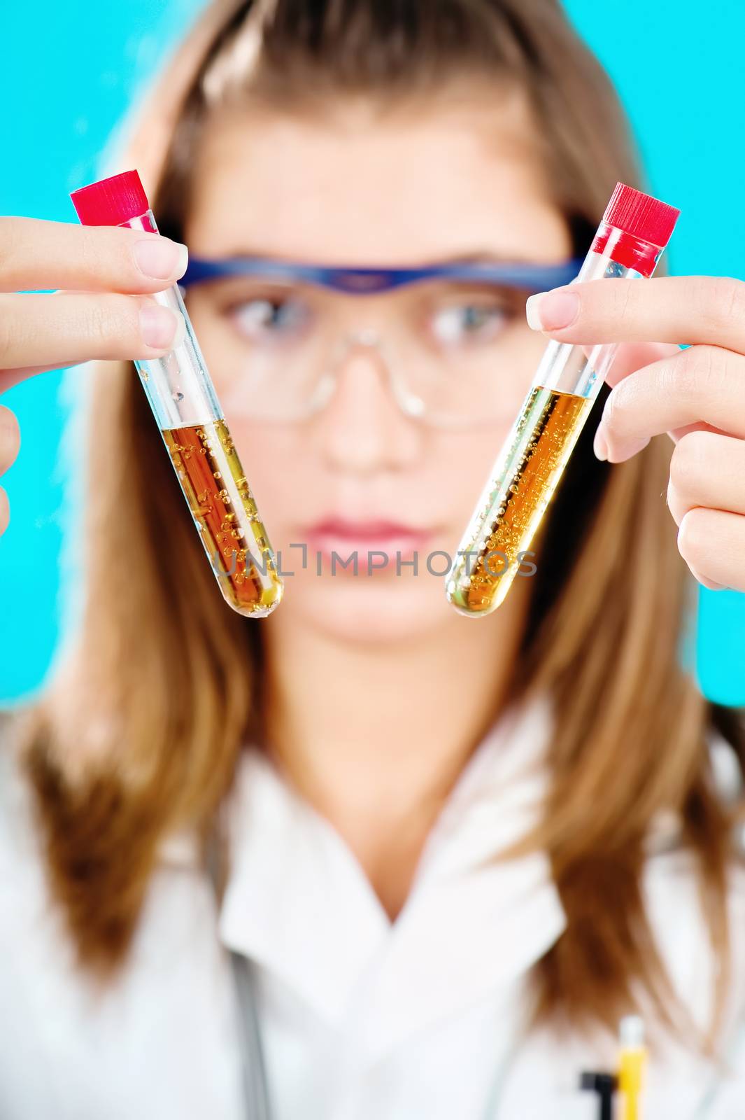 Young female doctor holding two chemical tubes, focus on tube