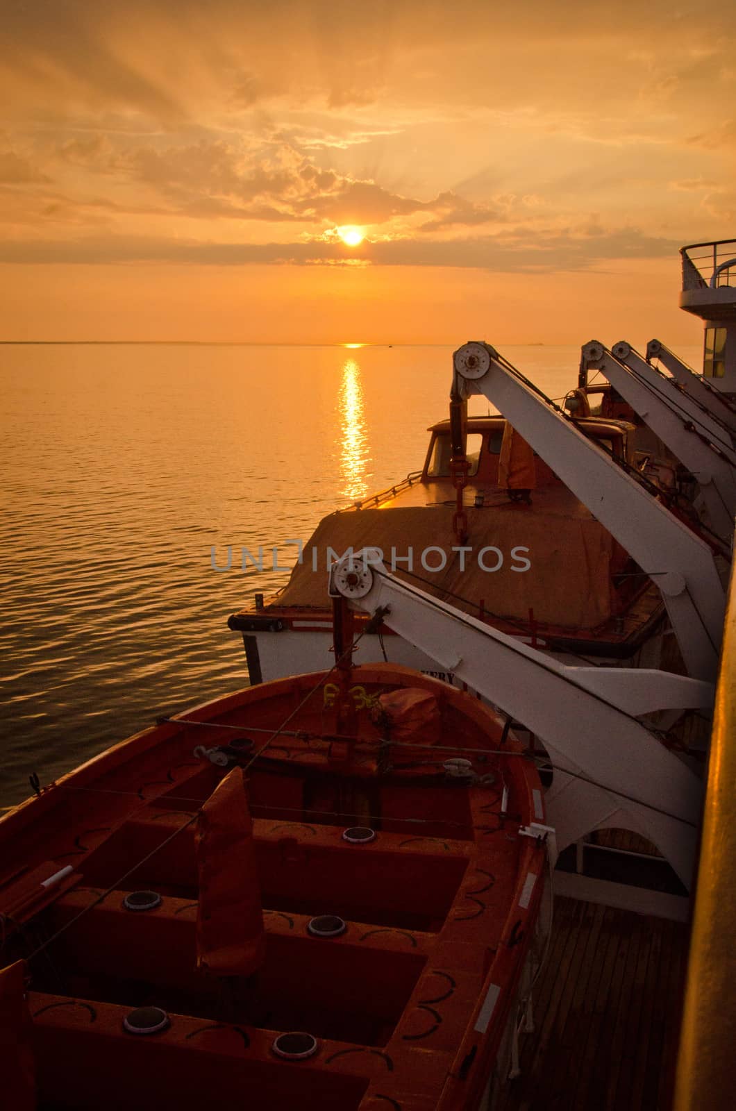 Sunset wtih lifeboats on a ship in the foreground