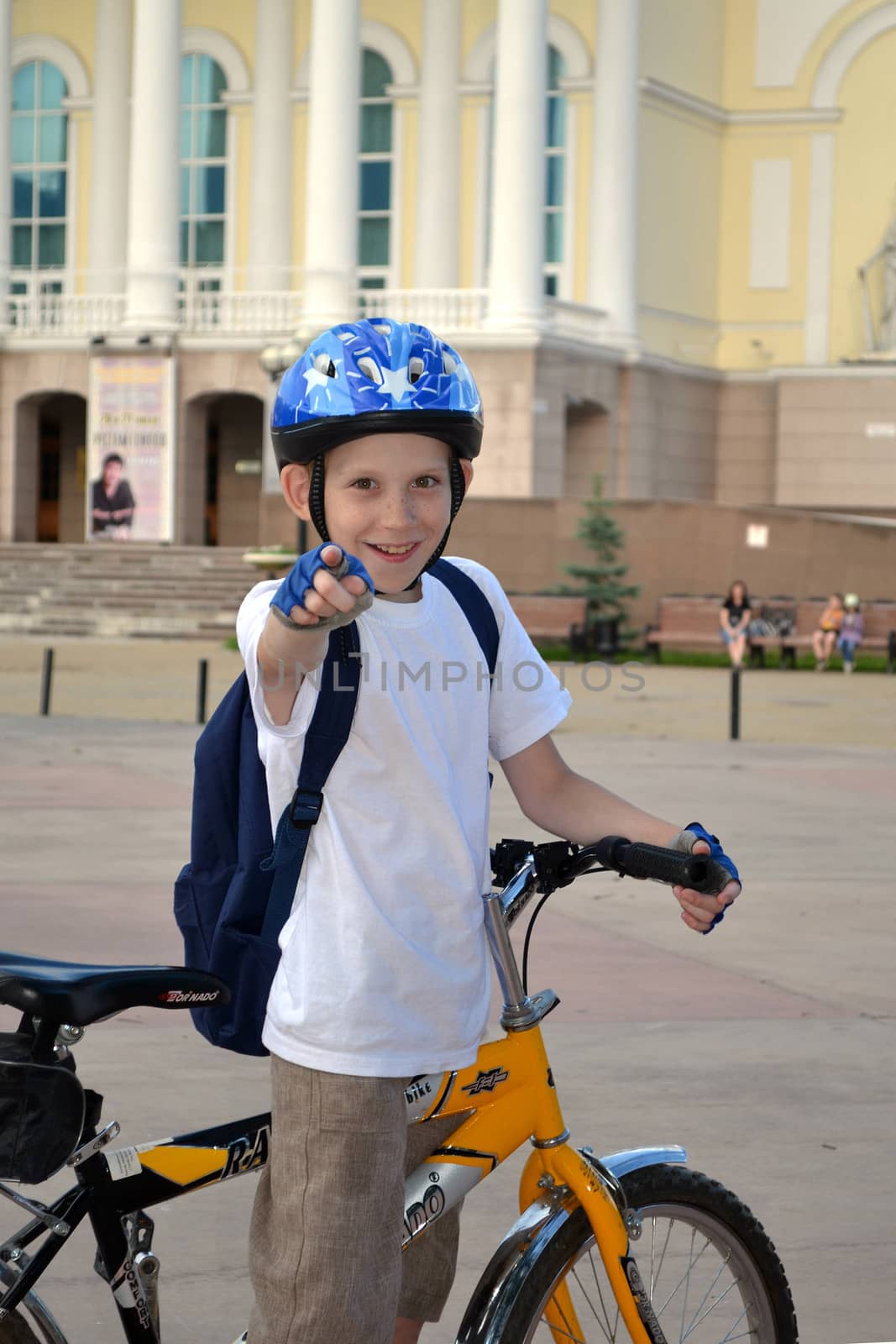 The teenager by bicycle near the Tyumen drama theater shows a forefinger in a shot.